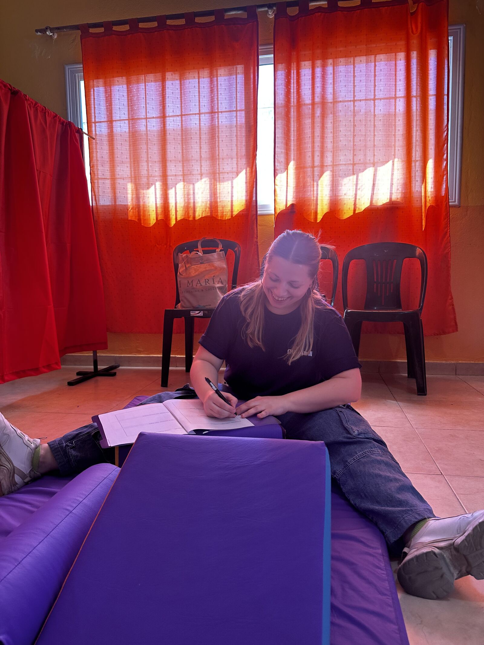 Una profesional de Goodwill toma notas en un cuaderno durante la admisión, sentada sobre las colchonetas