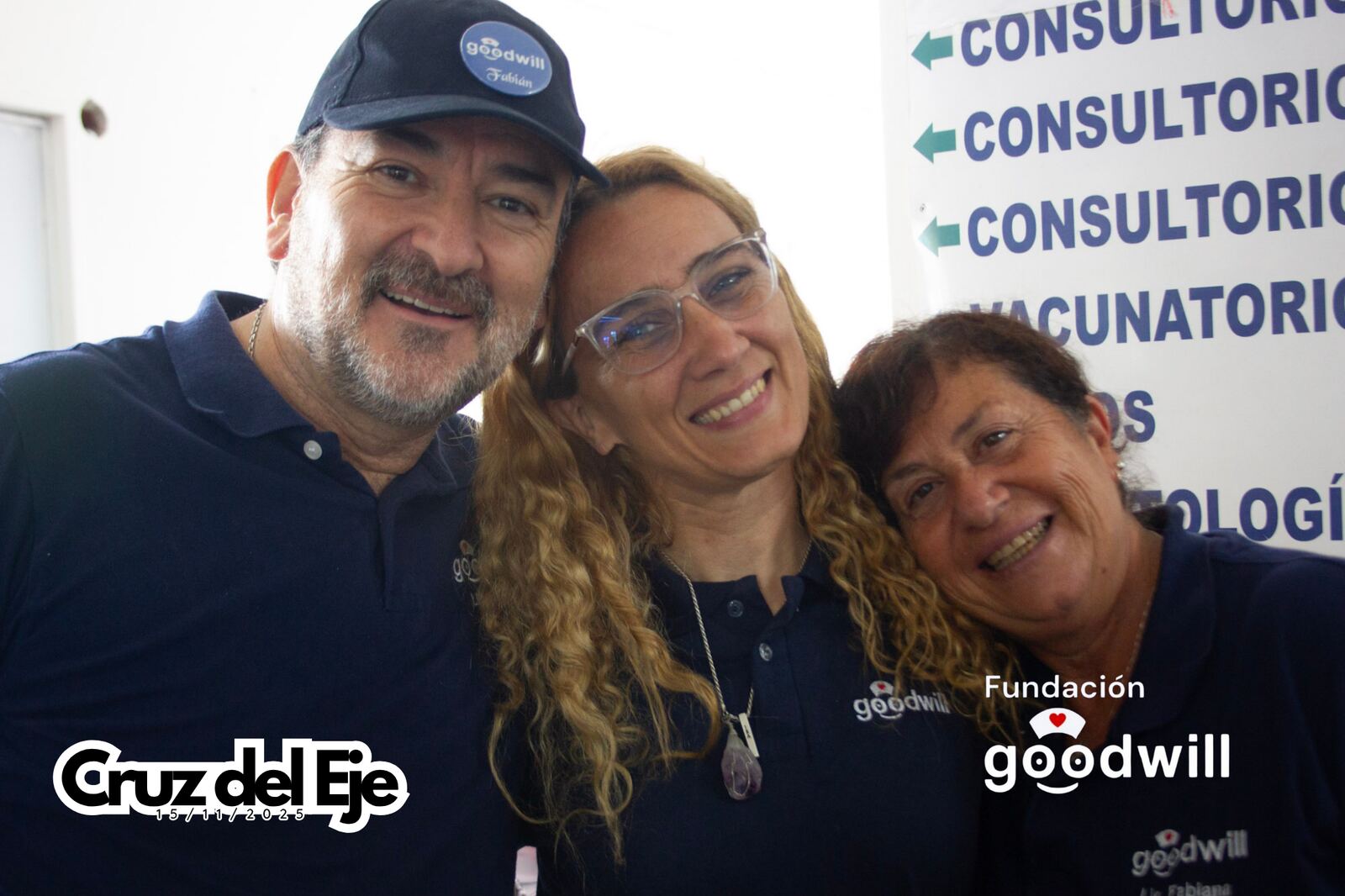 Tres integrantes del equipo de Goodwill sonríen frente a los carteles de los consultorios