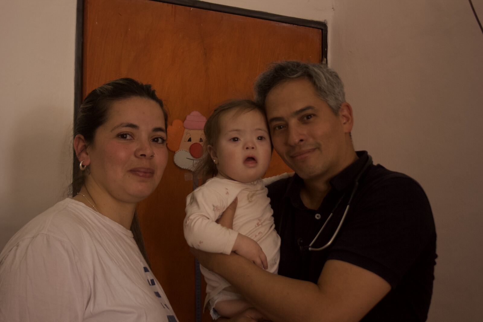 Una mamá y un médico de Goodwill con una beba en brazos, en la puerta del consultorio