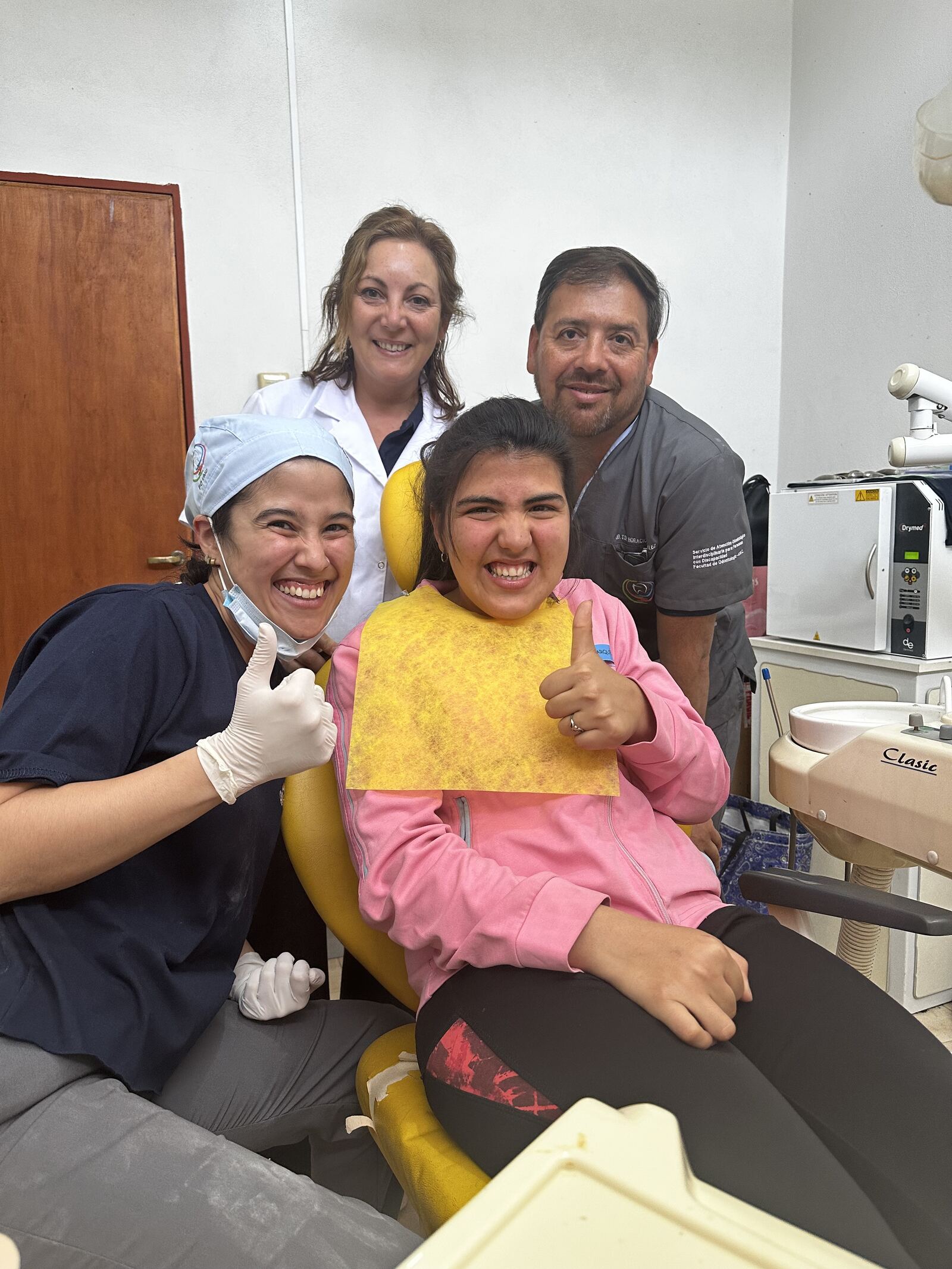 Consultorio odontológico: la paciente en el sillón y el equipo haciendo pulgar arriba.