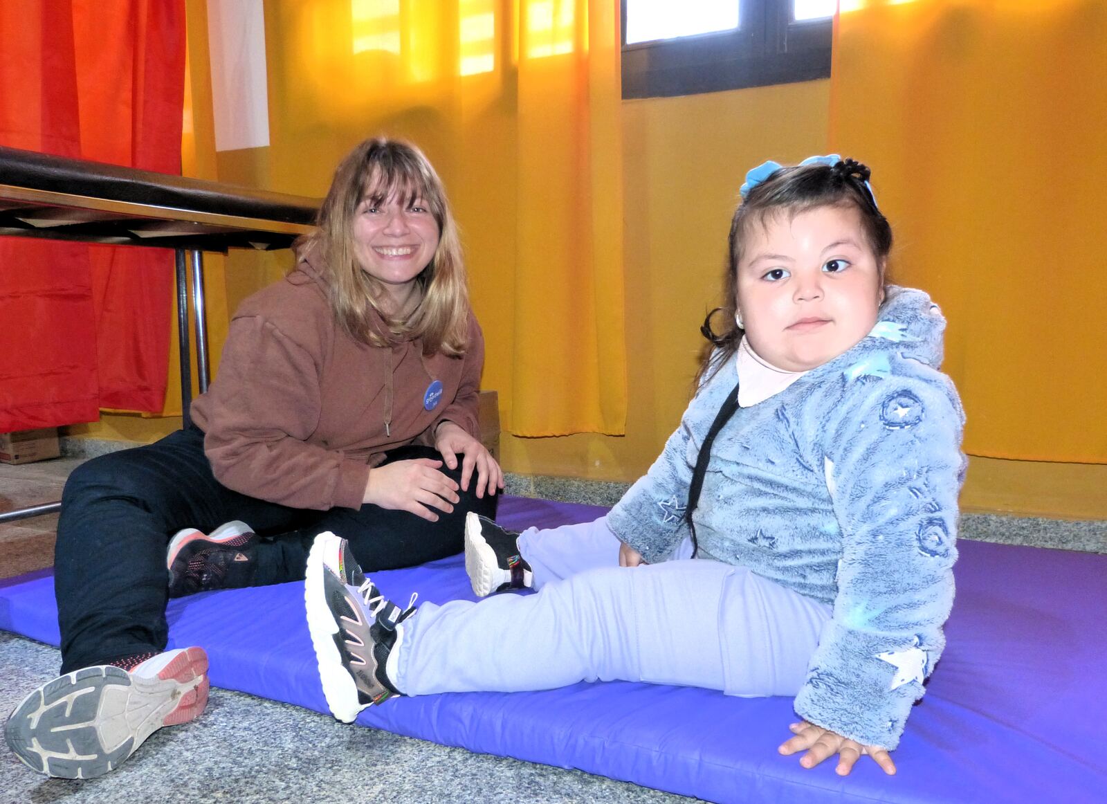 Una voluntaria sentada en la colchoneta acompaña a una nena durante un operativo
